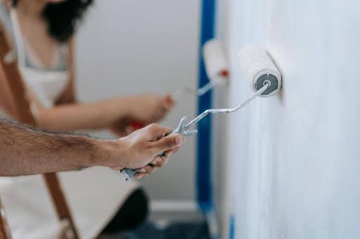 Painter preparing a wall with tools before interior painting, highlighting why surface preparation matters in Gold Coast homes.